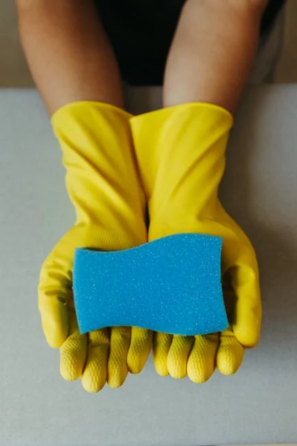 A professional cleaner in protective gear vacuuming the floor in a modern living room.